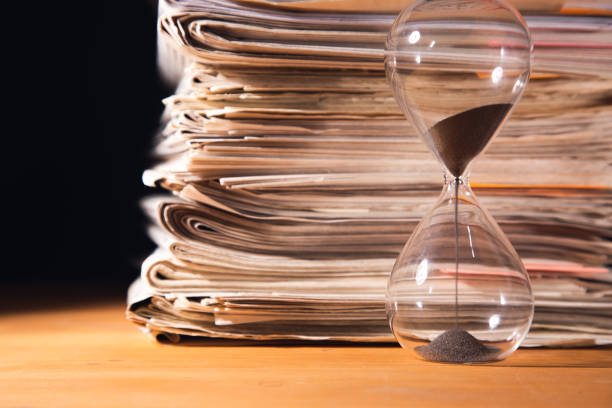 Pile of papers and hourglass on wooden table