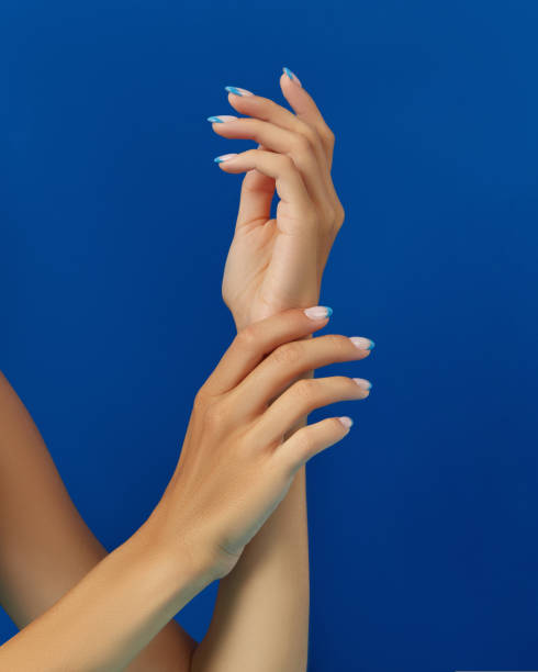 istock Beautiful womans hands trendy nail design on blue background. 1438477512