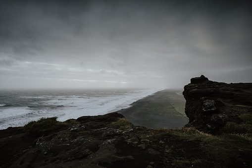 A beautiful scenery of the sea surrounded by rock formations enveloped in fog in Iceland