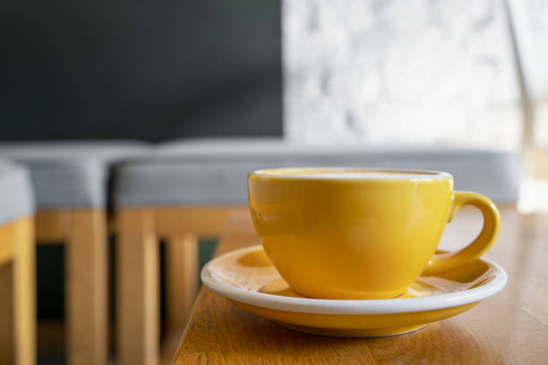 istock Yellow cup with coffee on a wooden table in a cafe. 1438479705