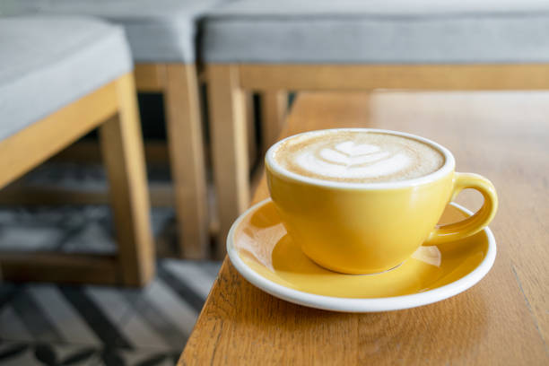 istock Yellow cup with cappuccino or latte coffee on a wooden table in a cafe. 1438479716