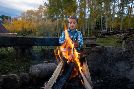 Three Young Farm Boy Enjoying a Campfire in the Forest Behind Their Homestead in the Mountains of Colorado Near Telluride