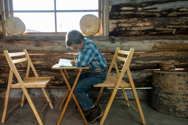 Young White Boy Doing Homework in an Old Fashioned One-Room School in the Mountains With Natural Window Light