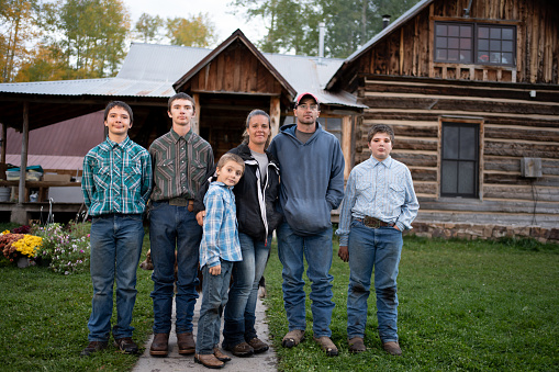 Young Family of Six, Mother, Father and Four Boys Posing Portrait In front of an old Log Cabin Home in Southwest Colorado Rocky Mountains Near Telluride