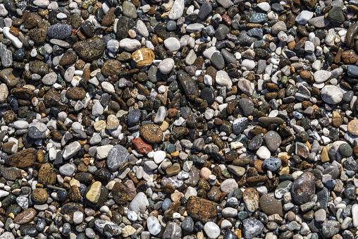 Tiny rocks along the shoreline of a Lake Michigan beach with bokeh background.