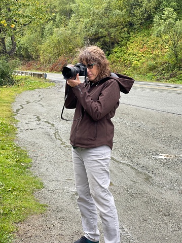 This woman is visiting Hatchers pass in the rain in Alaska and taking photographs of the beautiful landscape