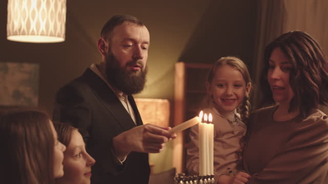 Jewish Family of Five Lighting Menorahs Together during Hanukkah