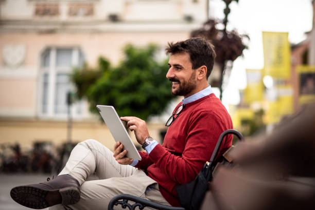 istock Handsome young man enjoying the nice weather while sitting on a bench outdoors 1438487491