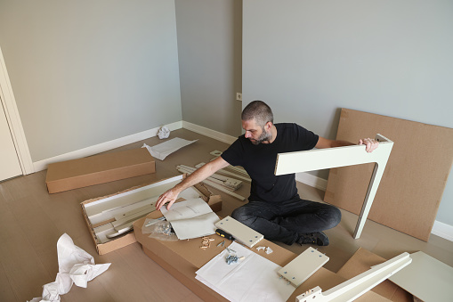 A man matches the parts of furniture by following the instructions