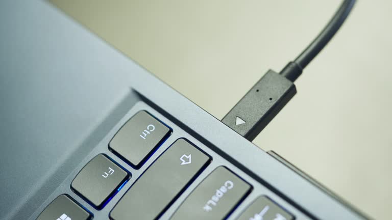 Close-up of hand plugging in usb type-c cable to computor laptop port. Data backup and transfer, mobile phone charger concept
