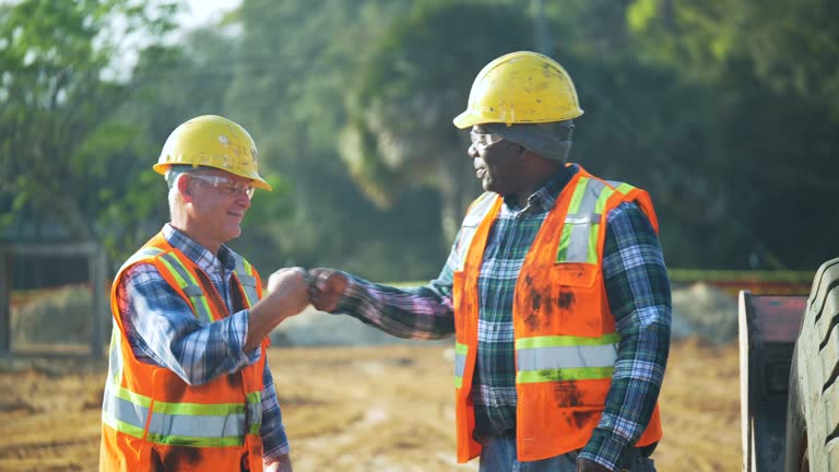 Two multiracial workers at construction site, fist bump