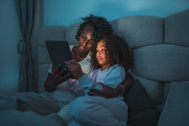 istock Black Mother And Mixed Race Daughter Using A Digital Tablet At Night 1438502451
