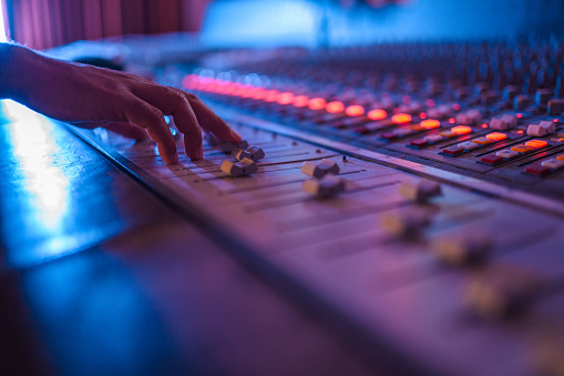 Shot of man's hand operating with sound recording studio mixer.