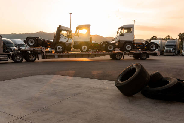 trucks being loaded onto a flatbed truck for transportation