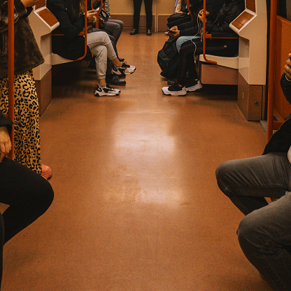 Unrecognizable traveling people sit in the subway and travel to their destination like work or vacation. There are no trademarks in the shot.