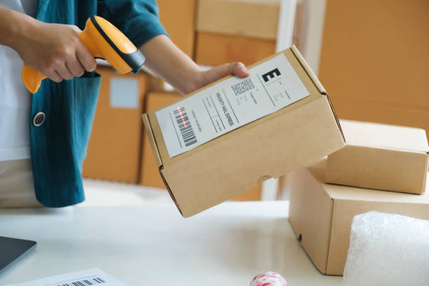 young entrepreneur scanning online order box. - cardboard box package box label imagens e fotografias de stock