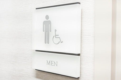 A men's room restroom sign on a solid wood door.
