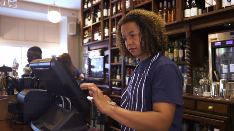 Waitress working at the pub and placing an order in the system using a computer