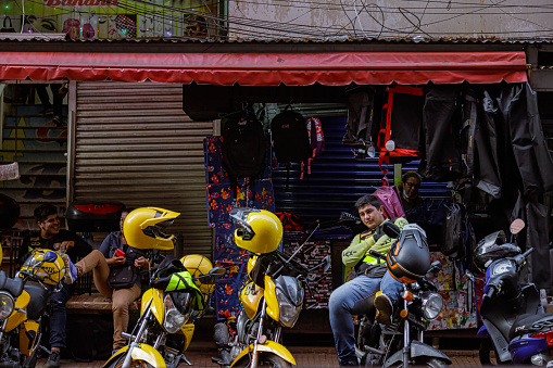 Ciudad del Este, Paraguay - July 27, 2022: Motorcycle taxi driver awaits customers aboard his motorcycle in the commercial area of the city
