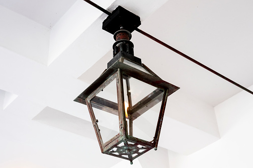 A decorative black hanging gas lantern with flame burning.