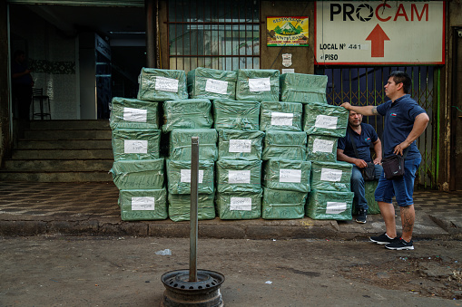 Ciudad del Este, Paraguay - July 27, 2022: Two delivery men wait with their packages inside the commercial area of the city