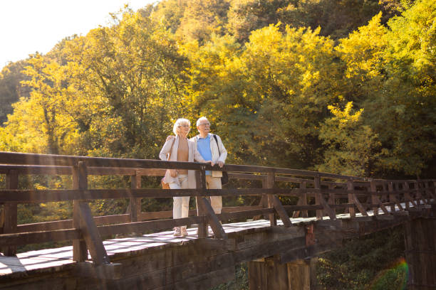 активный пенсионер - couple autumn embracing bridge стоковые фото и изображения