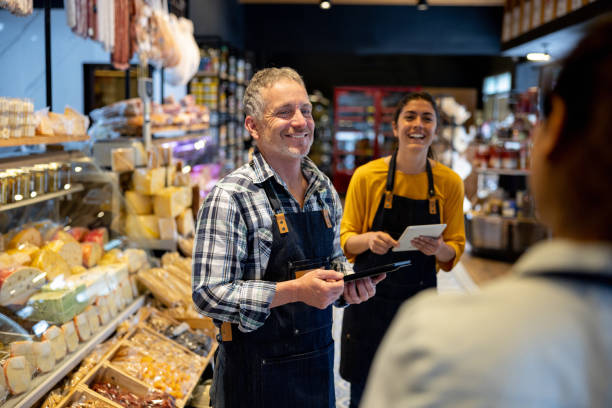 happy business owner talking to some employees at a supermarket - small business built structure retail imagens e fotografias de stock