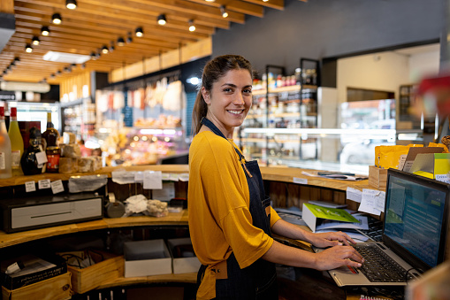 Portrait of a happy Latin American cashier working at the supermarket and looking at the camera smiling