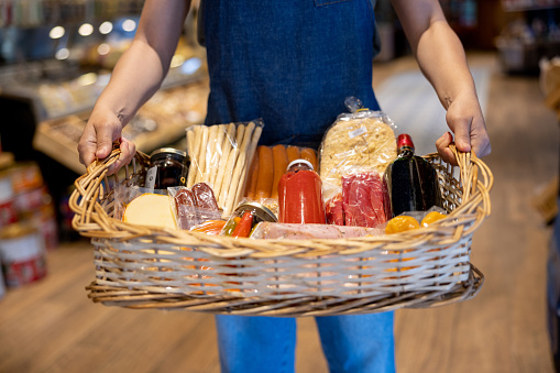 Close-up on a salesman working at a charcuterie and basket of food