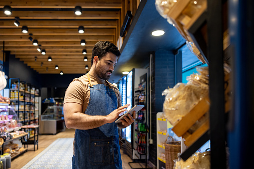 Retail clerk working at a food store and doing the inventory - small business concepts