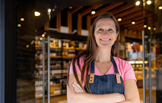 Portrait of a happy Argentinean woman working at a food shop and looking at the camera smiling