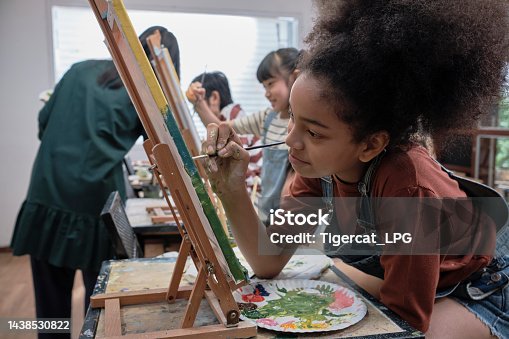 istock A girl concentrates on acrylic color painting on canvas in an art classroom. 1438530822