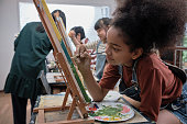 istock A girl concentrates on acrylic color painting on canvas in an art classroom. 1438530822