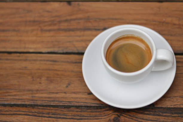 istock Espresso coffee in white ceramic cup on wooden table background. 1438538584