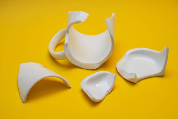 istock Splinters of the broken mug on a yellow background. 1438542702