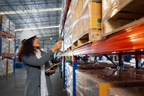 Asian woman with bar code reader checking digital tablet. Asian Woman worker working uses a barcode reader to scan a product inside boxes on a shelf rack to receive into an inventory system. radio frequency identification stock pictures, royalty-free photos & images