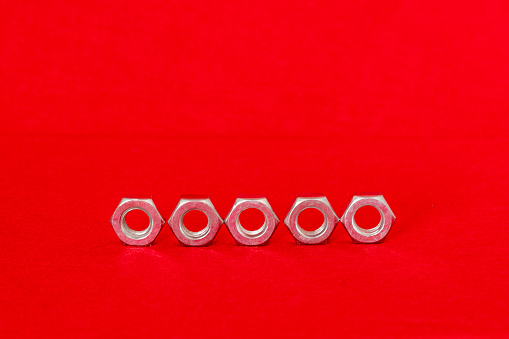 Image of five metal nut on red background