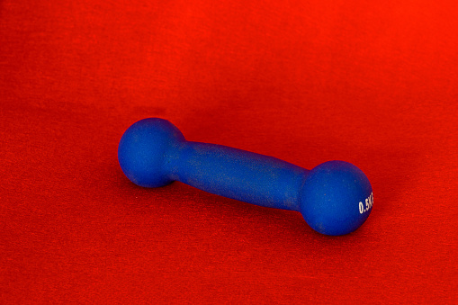 Blue dumbbell weights on red color background