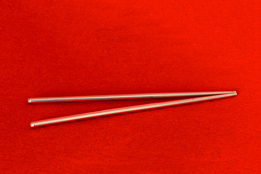 Silver metal chopsticks on red background