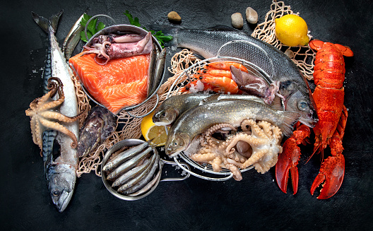 Fresh fish and seafood assortment on black background, fish market. Healthy diet eating concept. Top view.