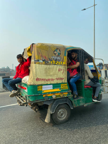 close-up image of indian auto rickshaw taxi cab travelling on highway, yellow and green tuk tuk transporting too many passengers, dangerous driving around connaught place, new delhi, india - consumerism indian ethnicity india delhi imagens e fotografias de stock