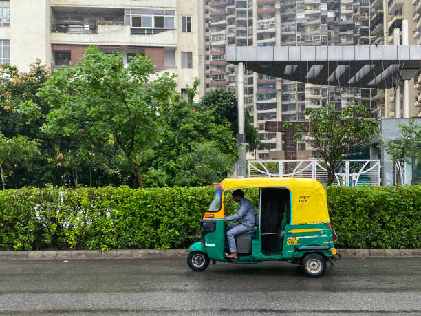 image of indian auto rickshaw taxi cab driver in yellow and green tuk tuk driving with no passengers, new delhi, india - consumerism indian ethnicity india delhi imagens e fotografias de stock