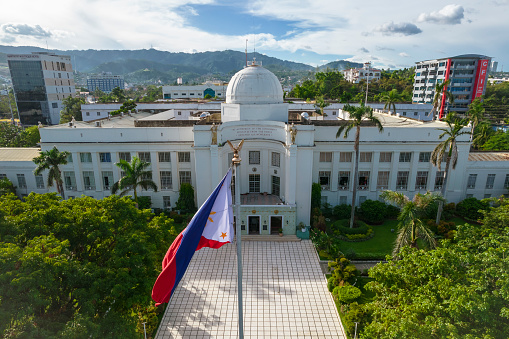 Cebu City, Philippines - May 2022: The Philippine Flag in front of the iconic Cebu Provincial Capitol Building.