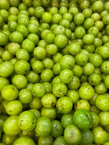 Stock photo showing close-up, elevated view of Indian gooseberries (Phyllanthus emblica) being sold in fruit and vegetable green grocer's section of supermarket, ready to eat for five a day healthy eating diet.