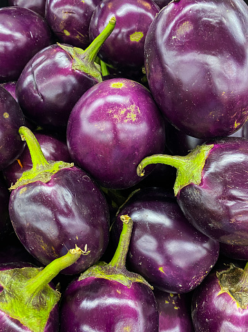 Stock photo showing close-up, elevated view of heap of aubergines being sold in fruit and vegetable green grocer's section of supermarket, ready to eat for five a day healthy eating diet.