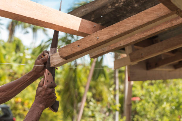 ein zimmermann sägt die überschüssige kante eines holzsparrens ab. bau oder rekonstruktion eines holzdachrahmens für ein ländliches haus. - reconstructing stock-fotos und bilder