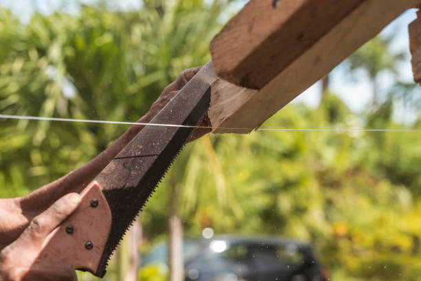 ein zimmermann sägt die überschüssige kante eines holzsparrens ab. bau oder rekonstruktion eines holzdachrahmens für ein ländliches haus. - reconstructing stock-fotos und bilder