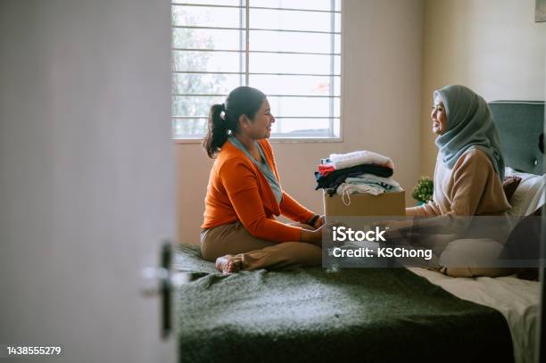 Mother And Daughter Preparing Clothes For Donating Stock Photo - Download Image Now - Charitable Donation, Malay People, Apartment