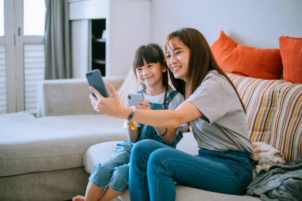 Asian Chinese mother and daughter making selfie and video call at home stock photo