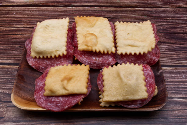 gnocco fritto mit salami auf rustikalem holztisch. italienischer ersatz für brot aus frittiertem teig. - gnocco fritto stock-fotos und bilder